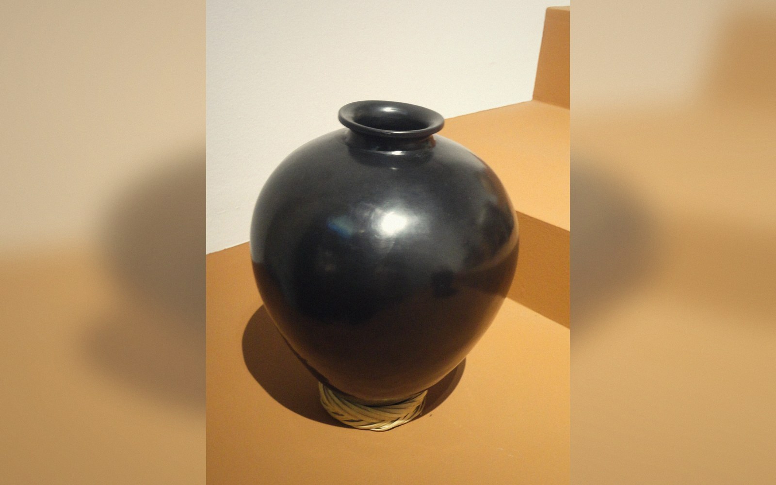Hand-thrown black clay pots stacked outside a kiln
