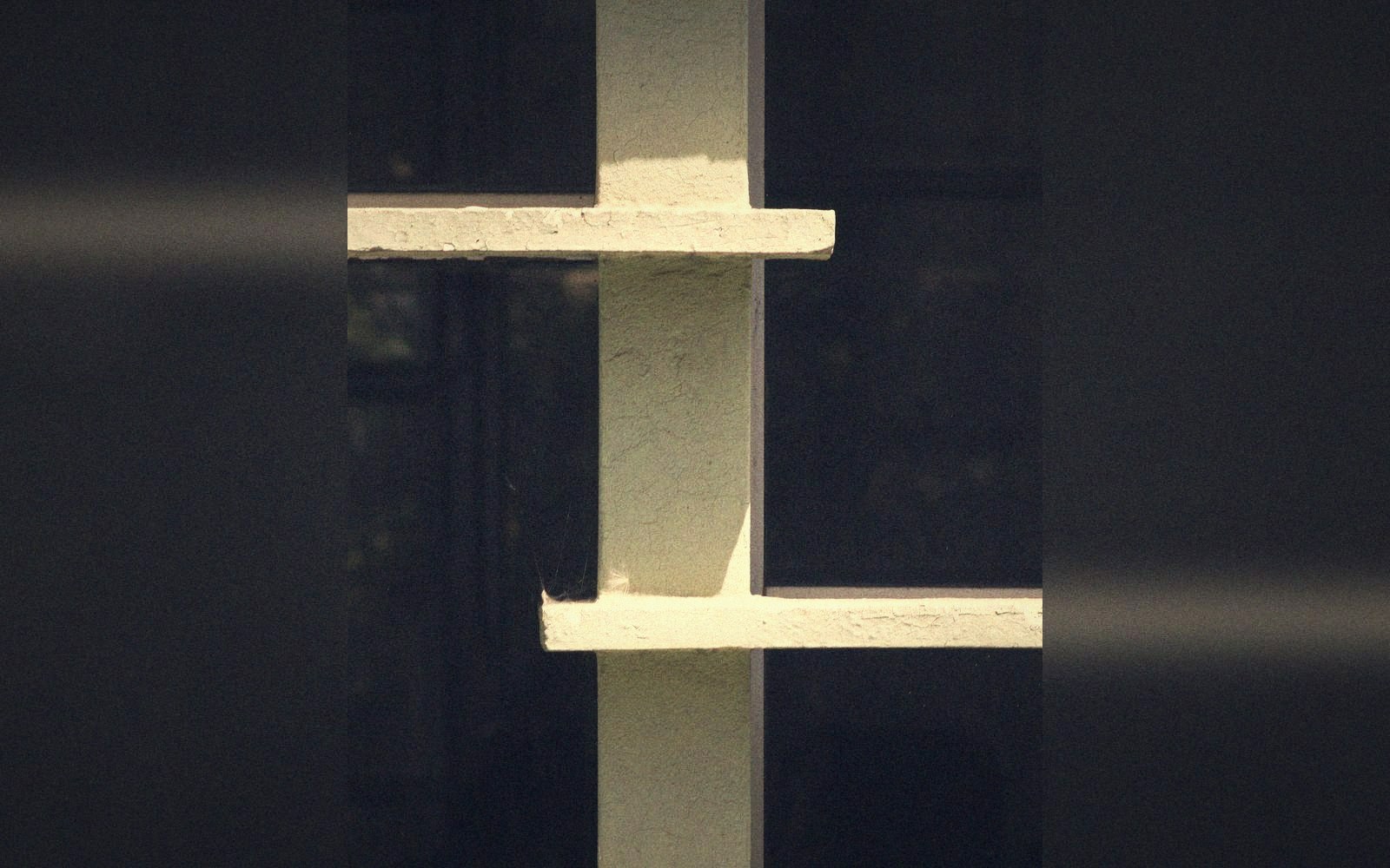 A deep concrete brise-soleil throwing hard bars of shade