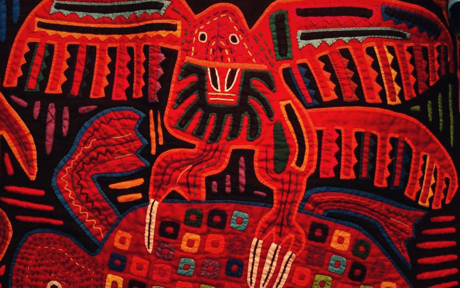 Reverse appliqué mola panel showing a stylized red bird figure with layered geometric patterns